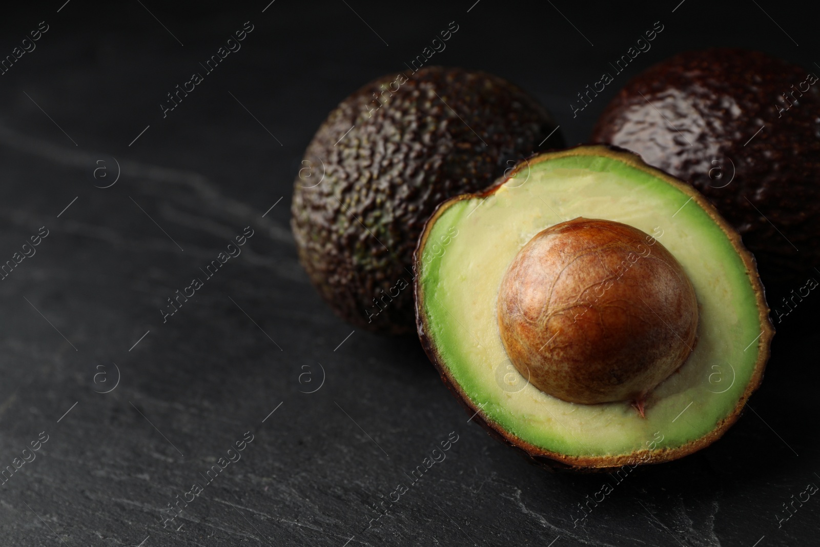 Photo of Delicious ripe avocado on dark grey table