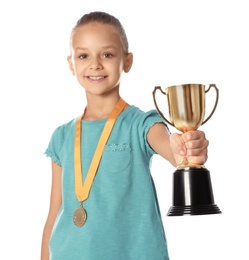 Photo of Happy girl with golden winning cup and medal on white background