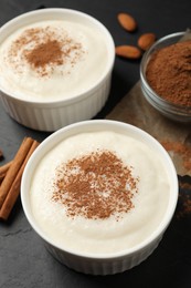 Photo of Delicious semolina pudding with cinnamon on black table