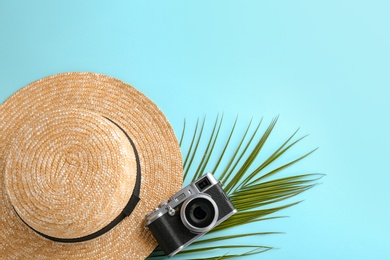 Stylish hat, camera and palm branch on color background, top view