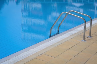 Photo of Outdoor swimming pool with handrails at resort on sunny day