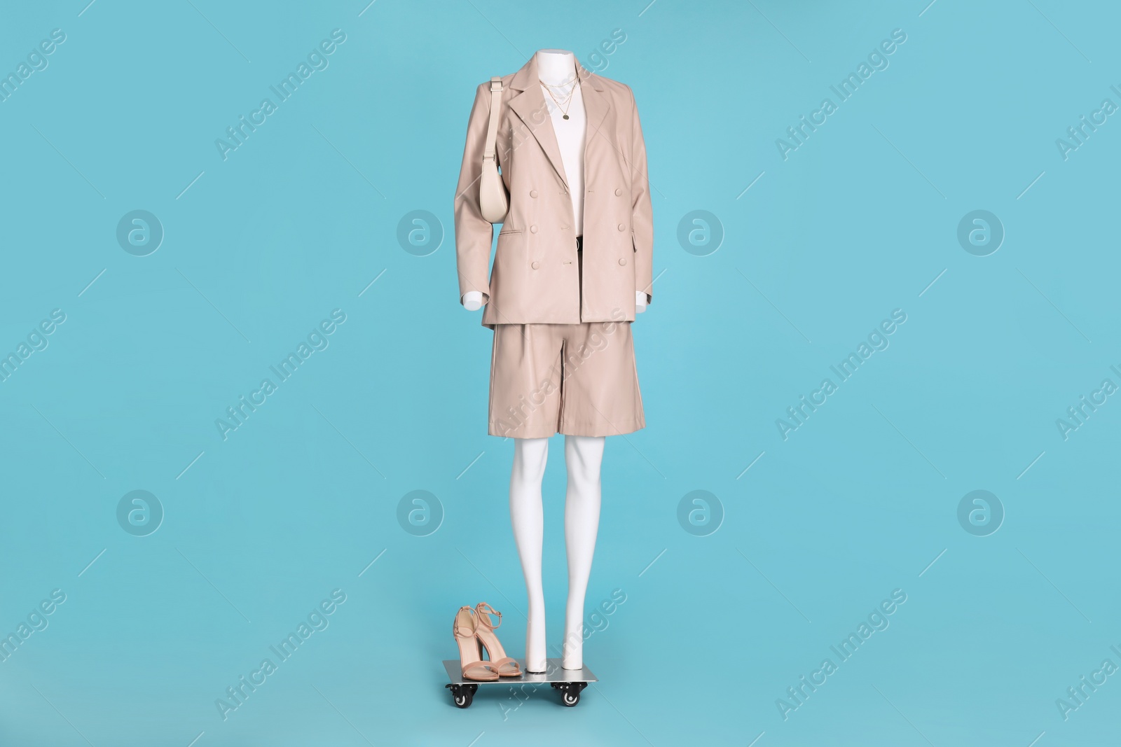 Photo of Female mannequin dressed in white t-shirt, stylish leather suit with accessories and shoes on light blue background