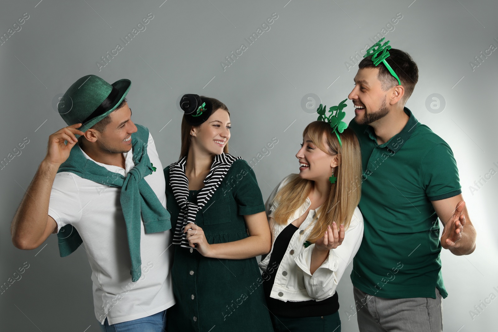 Photo of Happy people in St Patrick's Day outfits on light grey background