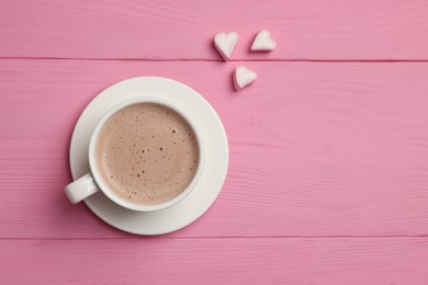 Cup of aromatic coffee and heart shaped marshmallows on pink wooden table, flat lay. Space for text