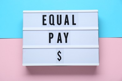 Photo of Lightbox with words Equal Pay on color background, top view