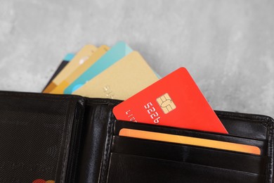 Photo of Many different credit cards and leather wallet on grey table, closeup