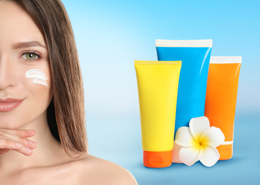 Image of Young woman and tubes with sun protection cream on light blue background
