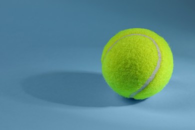 Photo of One tennis ball on light blue background, space for text