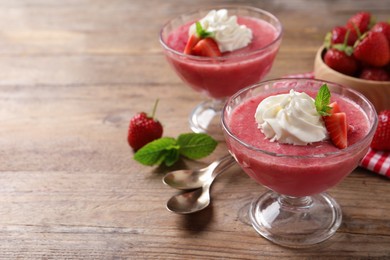 Photo of Delicious strawberry mousse with mint on wooden table, space for text