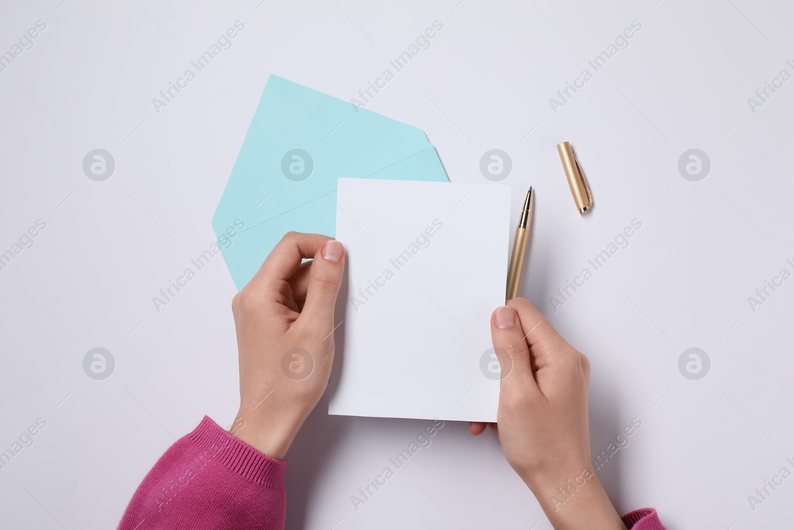 Photo of Woman with blank sheet of paper at white table, top view. Space for text