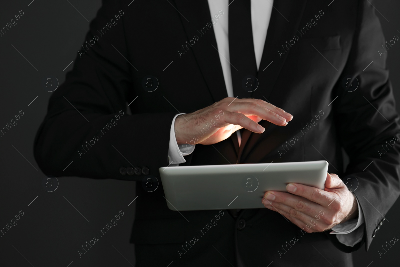 Photo of Closeup view of businessman using new tablet on black background