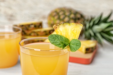 Photo of Glass with delicious pineapple juice on table, closeup