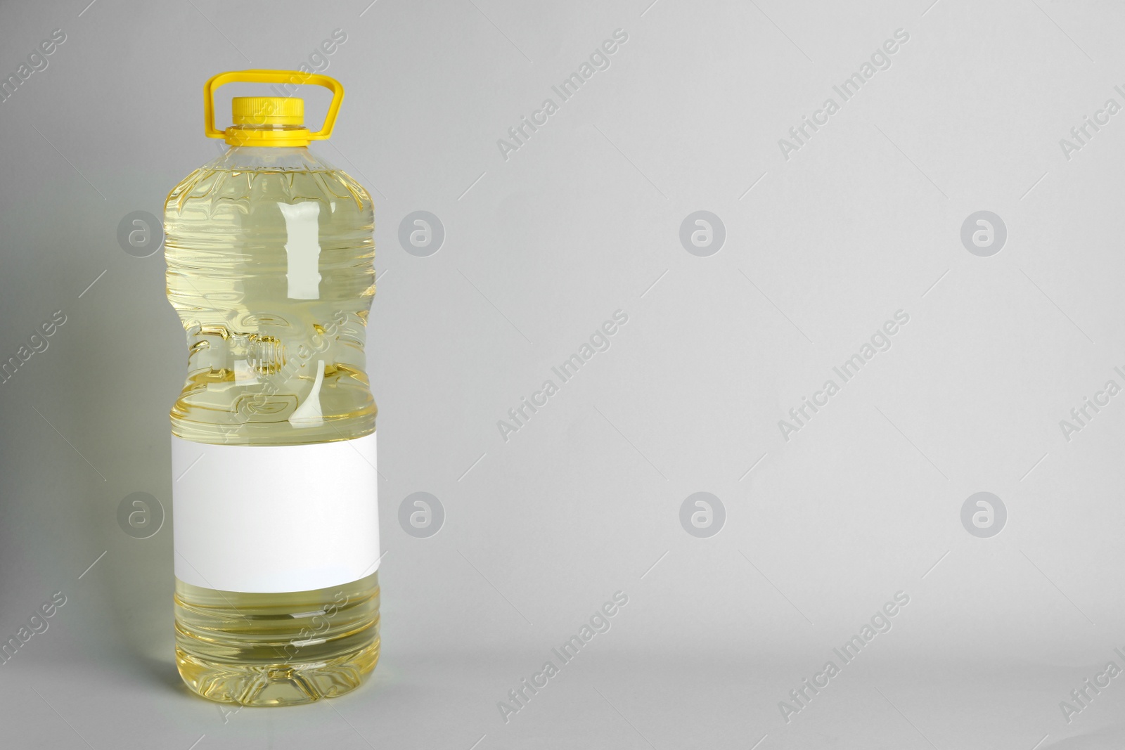 Photo of Bottle of cooking oil on light grey background. Space for text