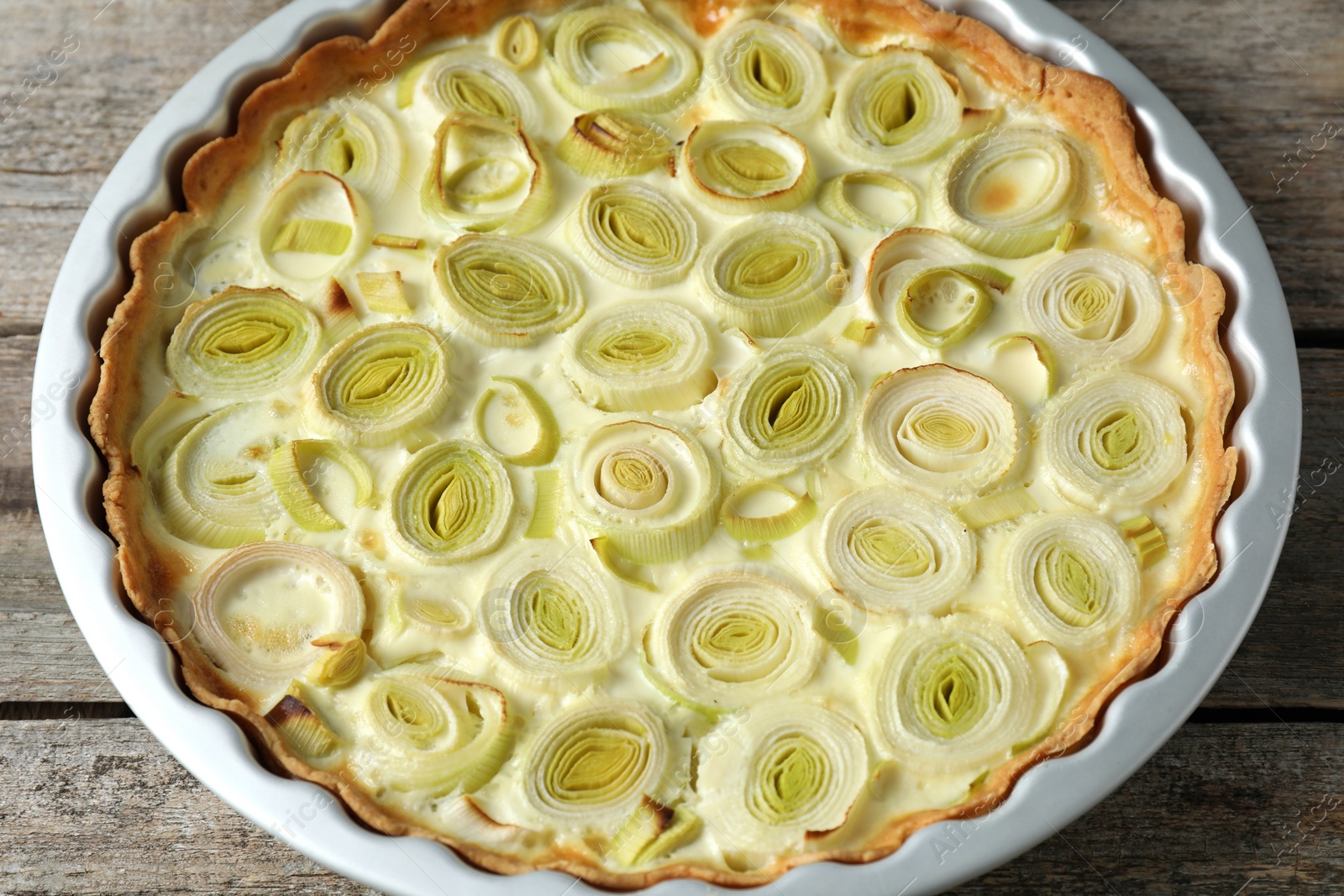 Photo of Tasty leek pie on old wooden table, closeup