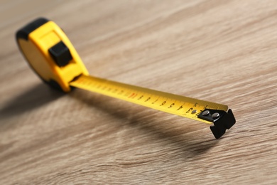 Metal measuring tape on wooden background. Construction tool