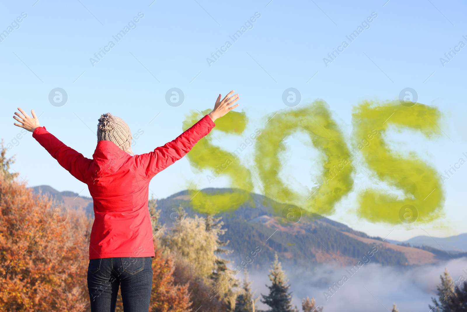 Image of Woman and word SOS made of color smoke bomb in mountains, back view