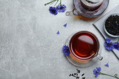 Photo of Flat lay composition with tea and cornflowers on light table. Space for text