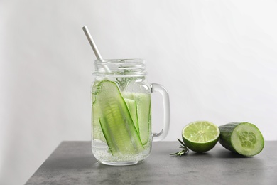 Photo of Mason jar with fresh cucumber water on grey table