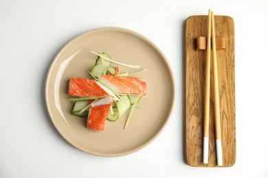 Photo of Fresh crab sticks with cucumber served on white table, flat lay
