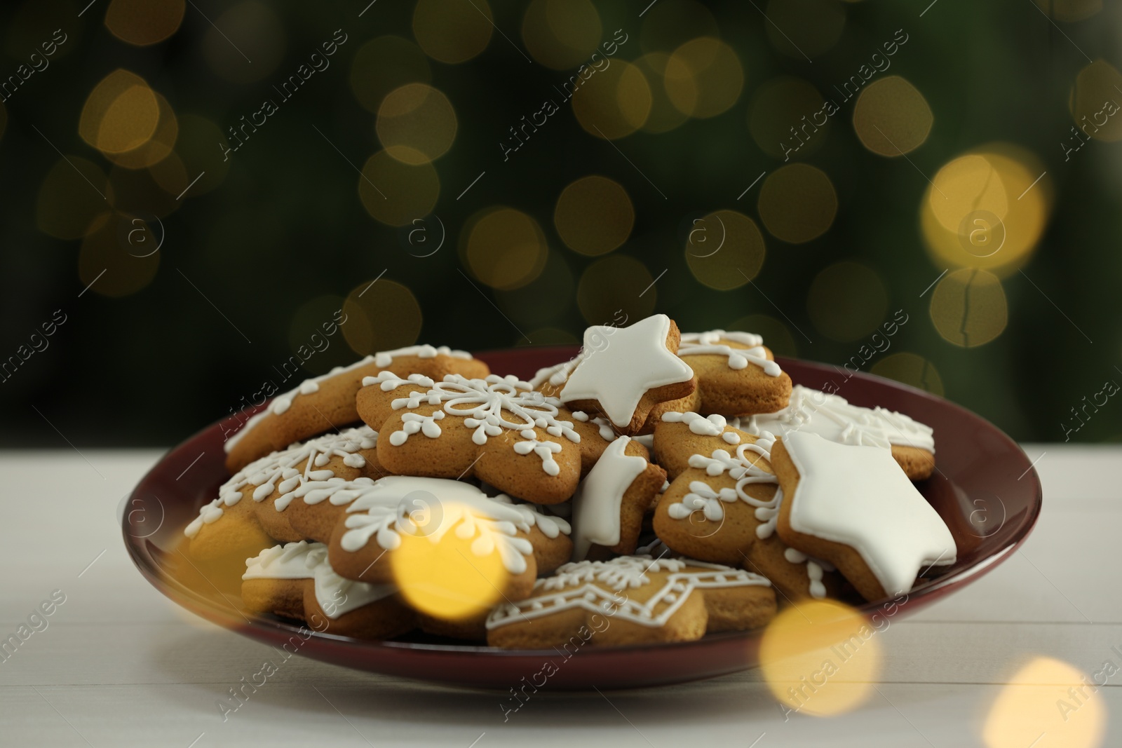 Photo of Decorated cookies on white against blurred Christmas lights