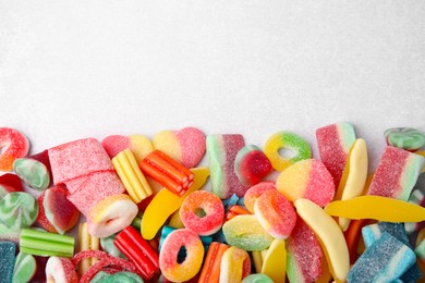 Many tasty colorful jelly candies on white table, flat lay. Space for text