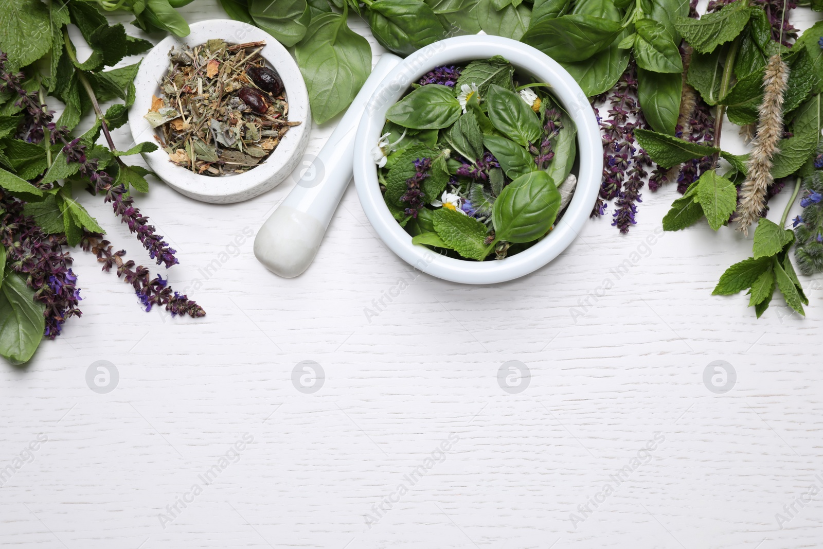 Photo of Flat lay composition with mortar and different healing herbs on white wooden table, space for text