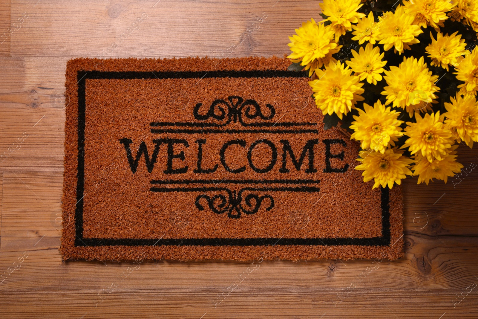 Photo of Doormat with word Welcome and beautiful flowers on wooden floor, flat lay