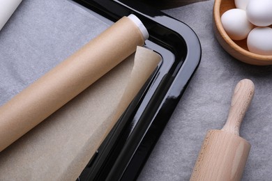 Baking pan with parchment paper, different ingredients and kitchen tool on table, flat lay