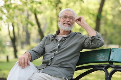 Portrait of happy grandpa with glasses on bench in park