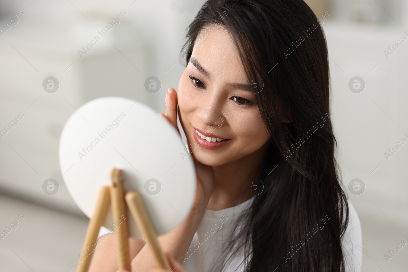 Photo of Woman with perfect skin looking at mirror indoors