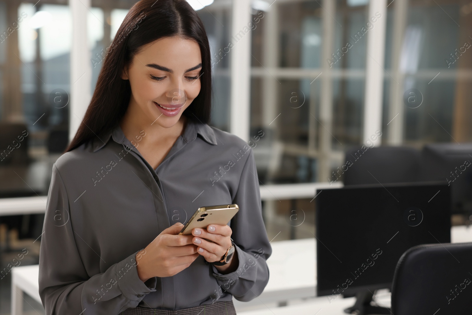 Photo of Smiling woman with smartphone in office, space for text. Lawyer, businesswoman, accountant or manager