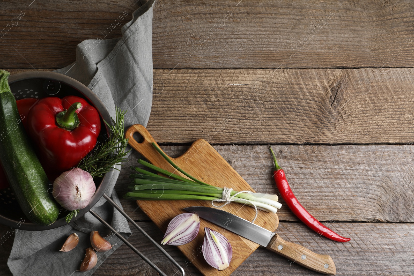 Photo of Cooking ratatouille. Vegetables, rosemary and knife on wooden table, flat lay with space for text