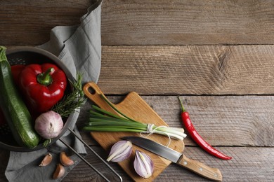 Cooking ratatouille. Vegetables, rosemary and knife on wooden table, flat lay with space for text