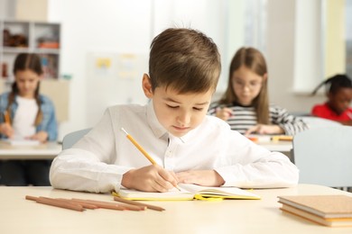 Portrait of cute little boy studying in classroom at school
