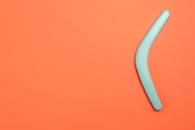 Photo of Turquoise boomerang on orange background, top view. Space for text