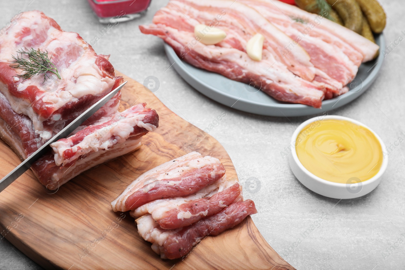 Photo of Cutting fresh pork fatback on grey table, closeup