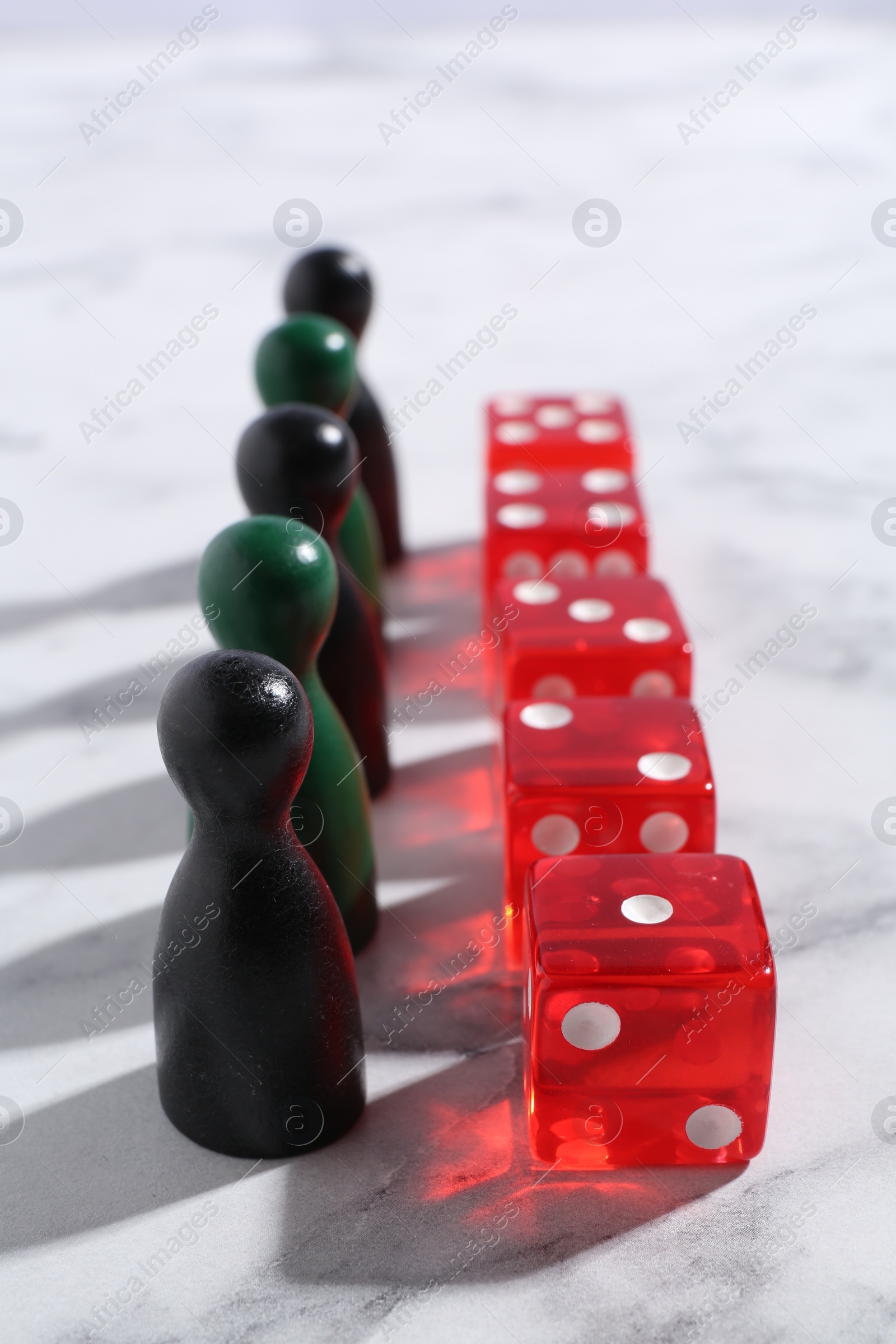 Photo of Red dices and color game pieces on white marble table