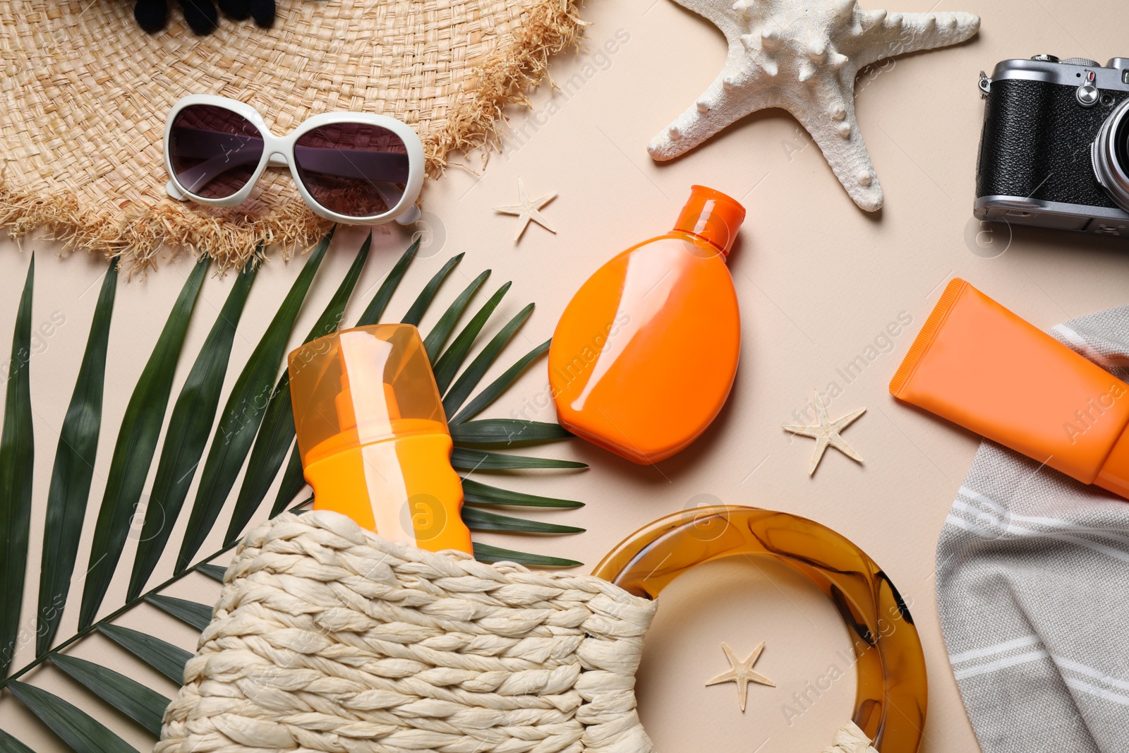 Photo of Flat lay composition with sun protection products and beach accessories on beige background