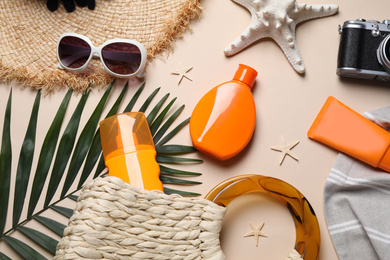 Photo of Flat lay composition with sun protection products and beach accessories on beige background
