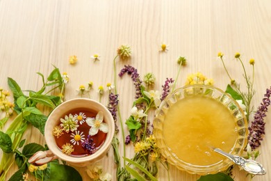 Cup of hot aromatic tea, honey and different fresh herbs on white wooden table, above view