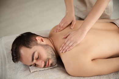 Handsome man receiving back massage in spa salon