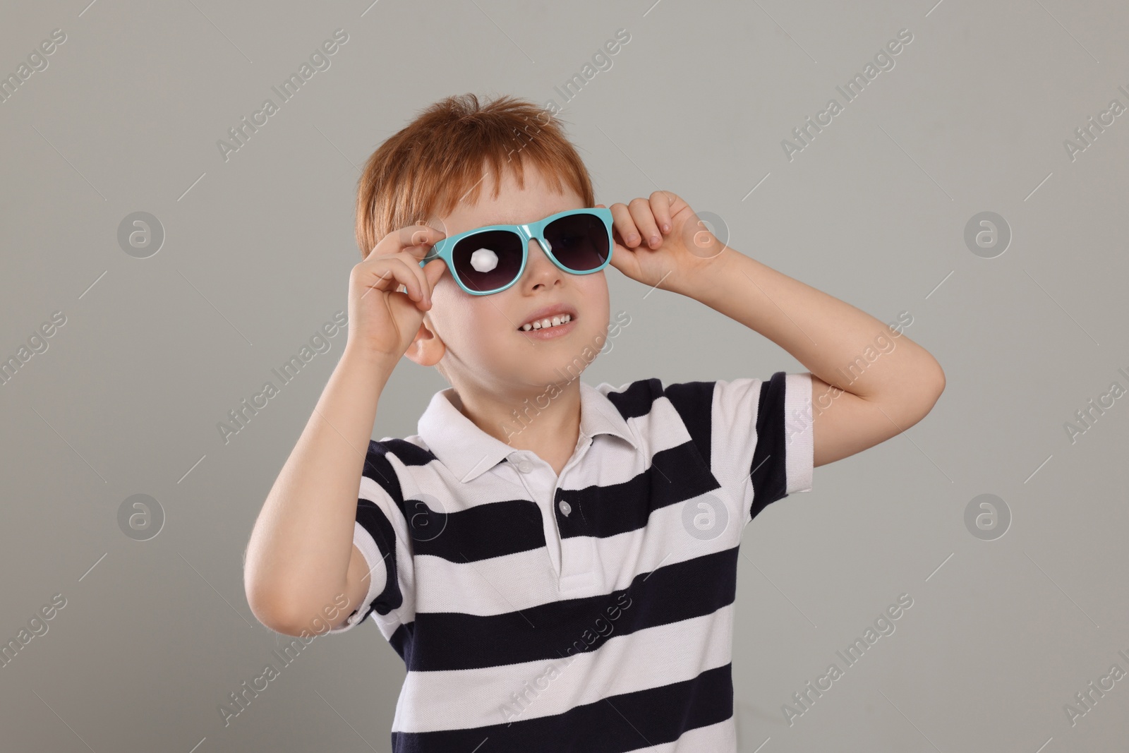 Photo of Cute little boy with sunglasses on light grey background