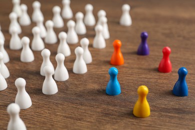 Photo of Colorful pawns on wooden table. Social inclusion concept