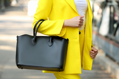 Photo of Young woman with stylish leather bag outdoors on summer day, closeup