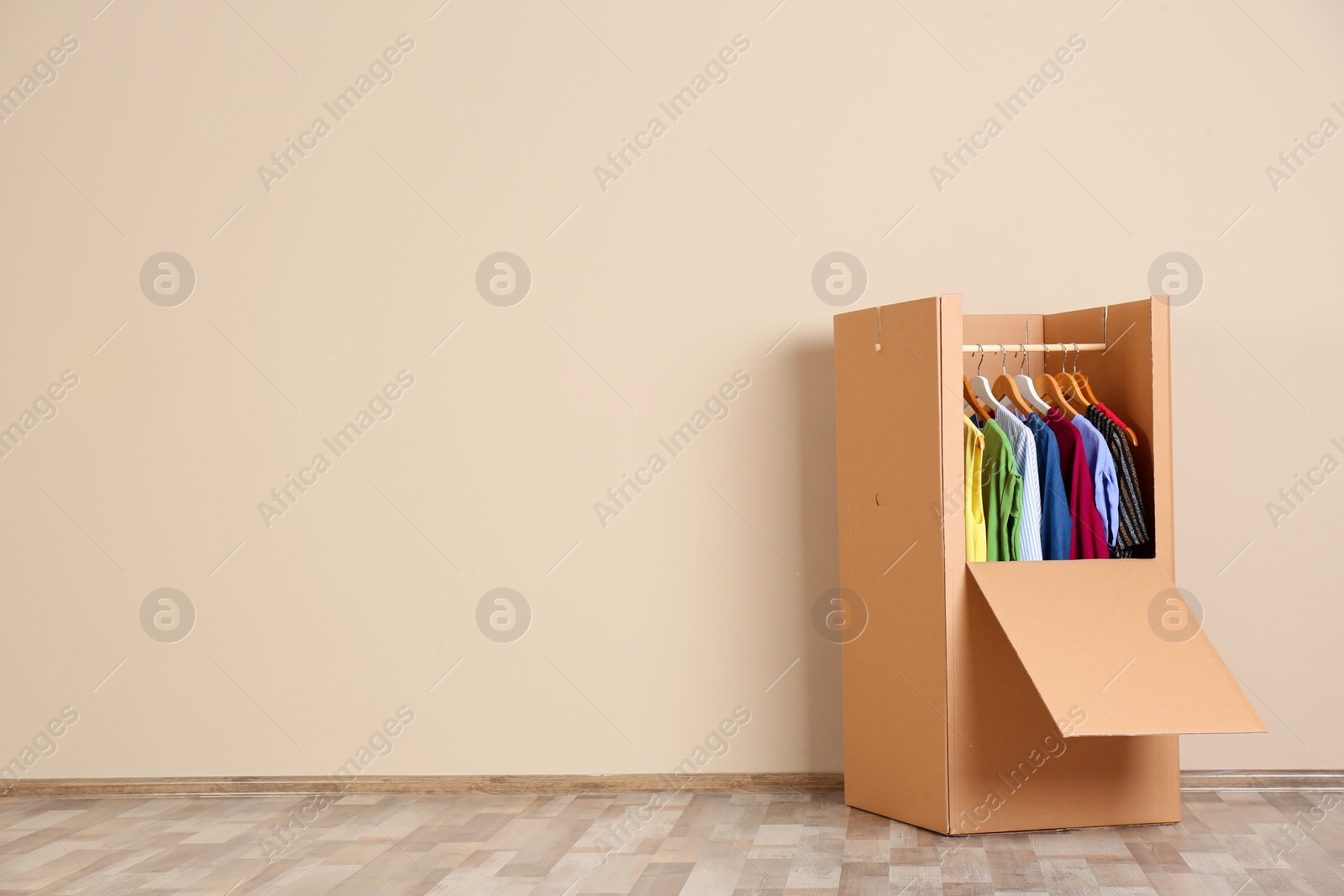 Photo of Wardrobe box with clothes against color wall indoors. Space for text