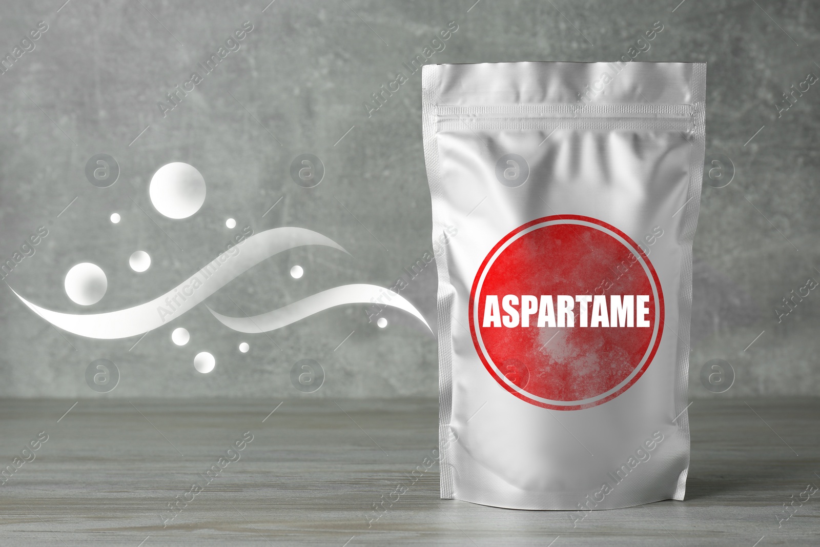 Image of Aspartame. Foil package with artificial sweetener on gray wooden table