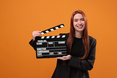Photo of Happy actress with clapperboard on orange background. Film industry