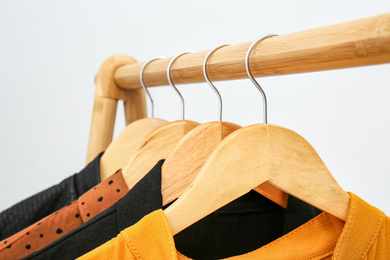 Wooden rack with stylish clothes on light background, closeup