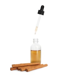 Image of Bottle of natural essential oil and dry cinnamon sticks on white background