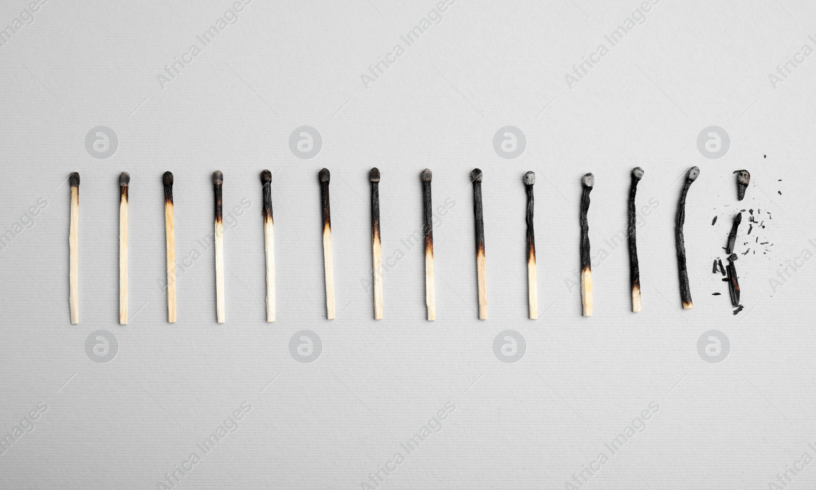Photo of Different stages of burnt matches on light background, flat lay